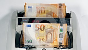 A stack of euro banknotes is getting counted mechanically