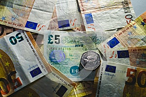 Stack of euro bills cornering a pound note by the brexit