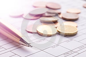 Stack of euro euro coins on old black wooden table. Pen and accounting documents with numbers