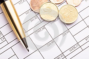 Stack of euro euro coins on old black wooden table. Pen and accounting documents with numbers