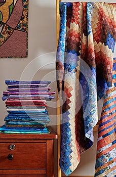 Stack of fabriÃÂs and quilt made in the bargello style on white wall background photo