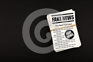 Stack of FAKE NEWS newspapers over black