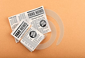 Stack of FAKE NEWS newspapers over brown paper