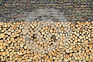 Stack of firewood against old weathered brick wall