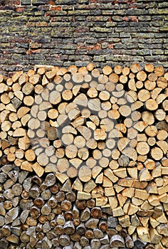 Stack of firewood on a old weathered brick wall background