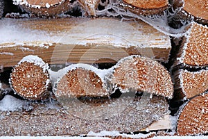 A stack of firewood with snow and hoarfrost in winter
