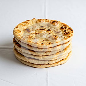 A stack of five round, flatbreads is arranged on a white surface