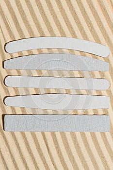 Stack of flexible emery boards of different shapes for manicures and pedicures on sandy background