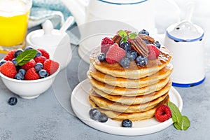 Stack of fluffy pancakes with fresh berries and pecan nuts