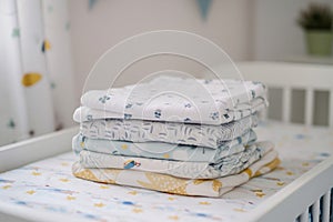 stack of folded baby garments on a changing table