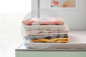 stack of folded baby garments on a changing table