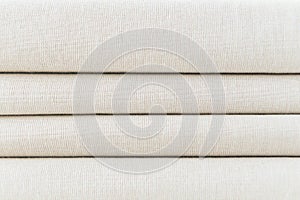 Stack of folded beige woven fabric patterned background