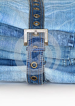 Stack of folded blue jeans with jean belt