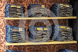 Stack of folded blue jeans pants on a shelf in a store.  Blue denim