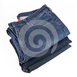 Stack of folded blue jeans on a white background