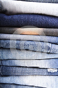 Stack of folded clothes, blue jeans pants, dark blue denim trousers on white background