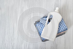 Stack of folded clothes and detergent bottle. Top view