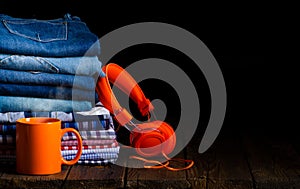 Stack folded jeans and clothes cage shirt, headphones, cup of tea, coffee