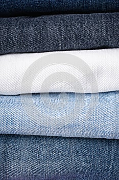 Stack of folded jeans, denim background, close-up