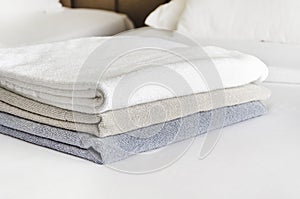 stack of folded terry towels lies on clean white bed. Cleaning in guest room of hotel, cleanliness