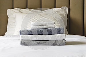stack of folded terry towels lies on clean white bed. Cleaning in guest room of hotel, cleanliness