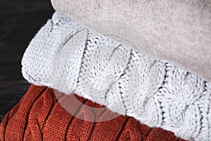 Stack of folded warm sweaters on black table, closeup