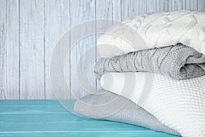 Stack of folded warm sweaters on turquoise wooden table. Space for text