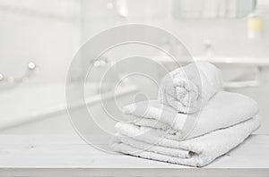 Stack of folded white spa towels over blurred bathroom background