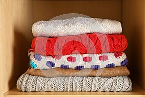 Stack of folded winter clothes on shelf
