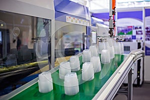 Stack of food containers on conveyor belt of plastic injection molding machine