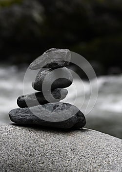 Stack of four rocks on a boulder by the river