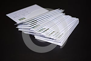 Stack of franked letters in white envelopes on black background