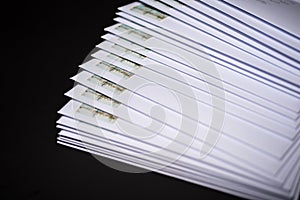 Stack of franked letters in white envelopes on black background