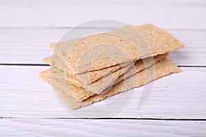 Stack of fresh crunchy rye crispbreads on white wooden table, closeup