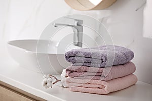 Stack of fresh towels and cotton flowers on countertop