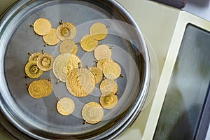 Stack of full, half and quarter Turkish gold coins on precision jeweler\'s scale