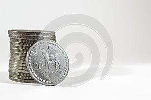 Stack of Georgian Lari coins with a 20 Lari coin leaning on it on a white background