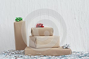 Stack of gifts in kraft paper with bow of green, red and silver colors. Plaster wall. Copy space, mock up