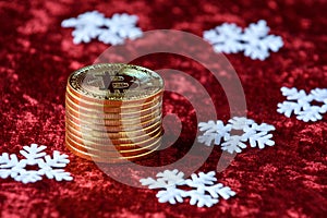 Stack of gold bitcoins on a red velvet background, with white Snowflakes