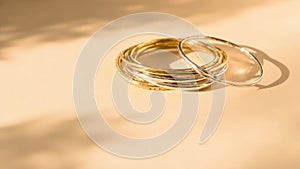 A stack of gold and silver bangles rests on a softly lit surface