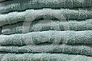 Textured green bath towels stacked close up.