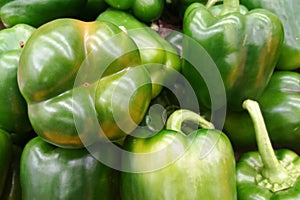 Stack of green bell peppers on a market stall