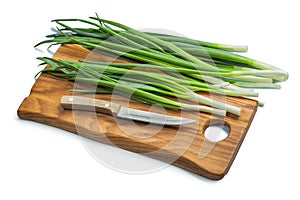 Stack Of Green Onions And Kitchen Knife On Wooden Chopping Board Isolated