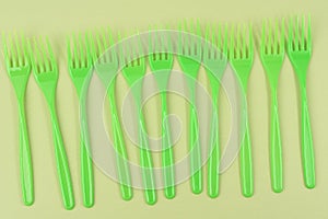 stack of green plastic forks on a green background