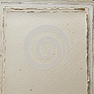 Stack of handmade paper with rough, deckled edges. Textured surface in a light beige
