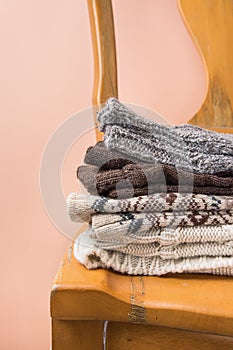 Stack of Handmade Warm Knitted Socks Scarfs Mittens Sweaters From Rough Wool Yarn Brown Beige Grey Vintage Chair Peach Color Wall