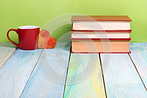 Stack of hardback books, diary on wooden deck table and green background. Back to school. Copy Space. Education