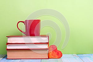 Stack of hardback books, diary on wooden deck table and green background. Back to school. Copy Space. Education