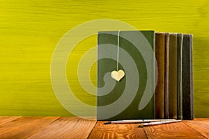 Stack of hardback books, diary on wooden deck table and green background. Back to school. Copy Space. Education