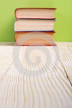 Stack of hardback books, diary on wooden deck table and green background. Back to school. Copy Space. Education